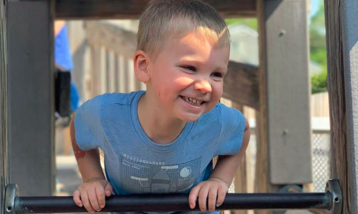 Happy young little boy enjoying climbing the bars on a playground at a Preschool & Daycare Serving Hampton Roads, VA