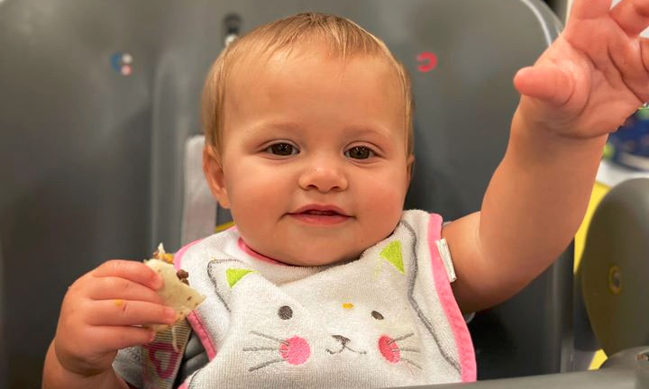 Cute little baby wearing bib while eating at a Preschool & Daycare Serving Hampton Roads, VA