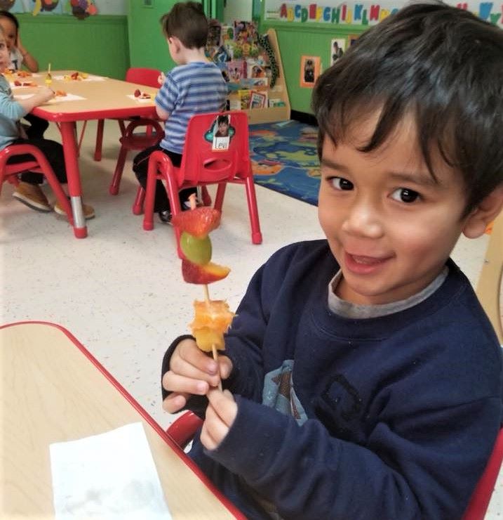 A preschool boy putting some chunks of different fruits for their school activity at a Preschool & Daycare Serving Hampton Roads, VA