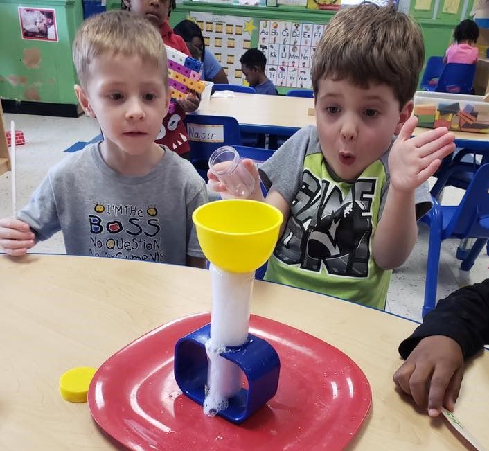 Two young boys getting amazed by the chemical reaction from their school chemistry experiment at a Preschool & Daycare Serving Hampton Roads, VA
