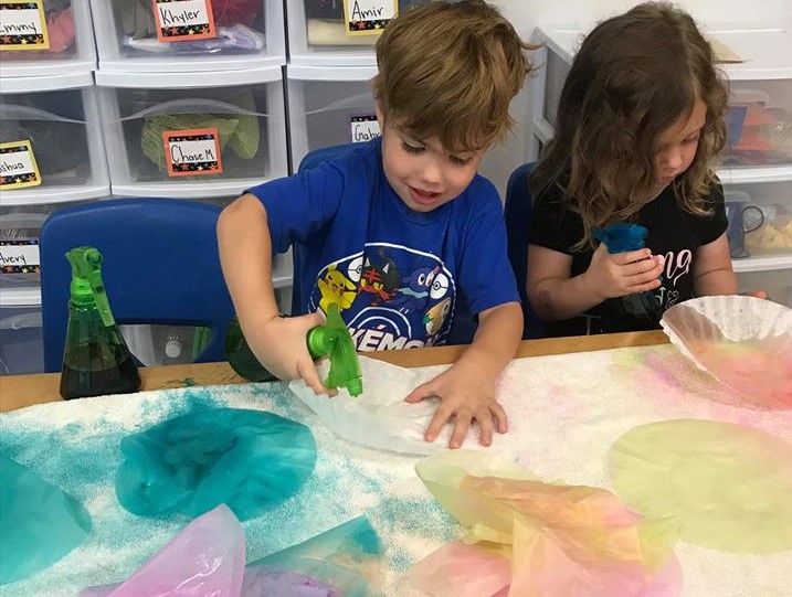 Preschoolers spraying some colored water in a spray bottle having fun on their water coloring art activity at a Preschool & Daycare Serving Hampton Roads, VA