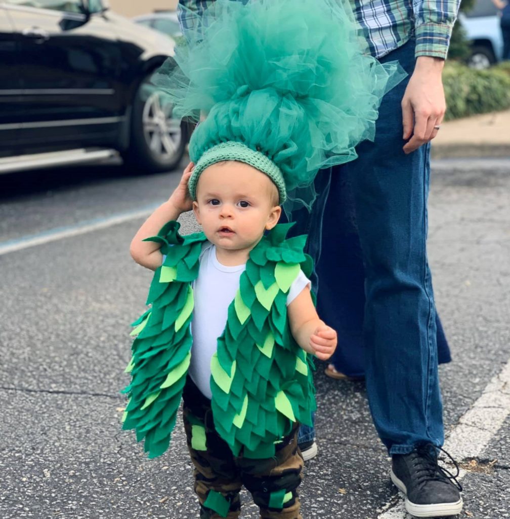 A young little boy wearing a green tree-like leafy costume on a parade at a Preschool & Daycare Serving Hampton Roads, VA