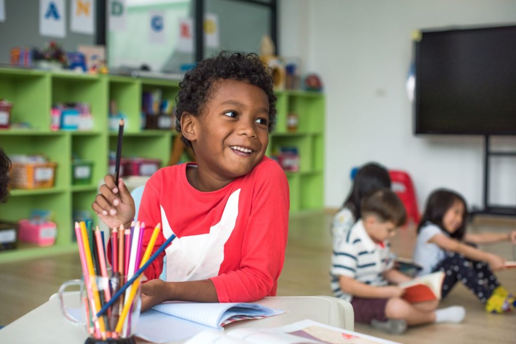 Happy african american preschool preparing for their writing activity at a Preschool & Daycare Serving Hampton Roads, VA