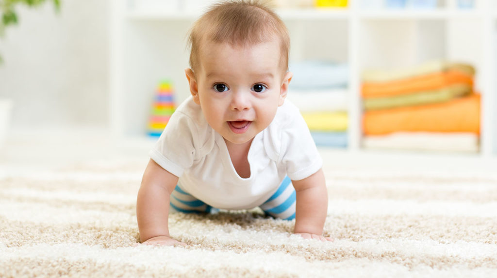 Nursery baby boy crawling on floor indoors at home at a Preschool & Daycare Serving Hampton Roads, VA