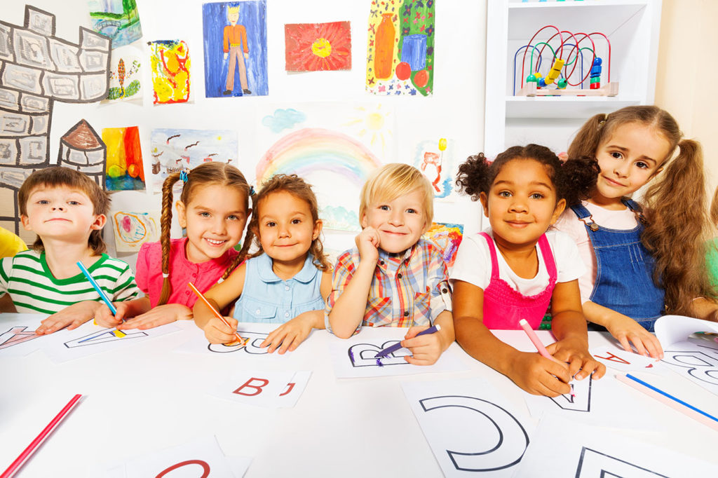 Group of diverse looking boys and girls in kindergarten class drawing letters in early reading class at a Preschool & Daycare Serving Hampton Roads, VA