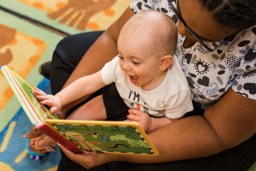 Happy cute little baby boy enjoying the storytelling of the teacher at a Preschool & Daycare Serving Hampton Roads, VA