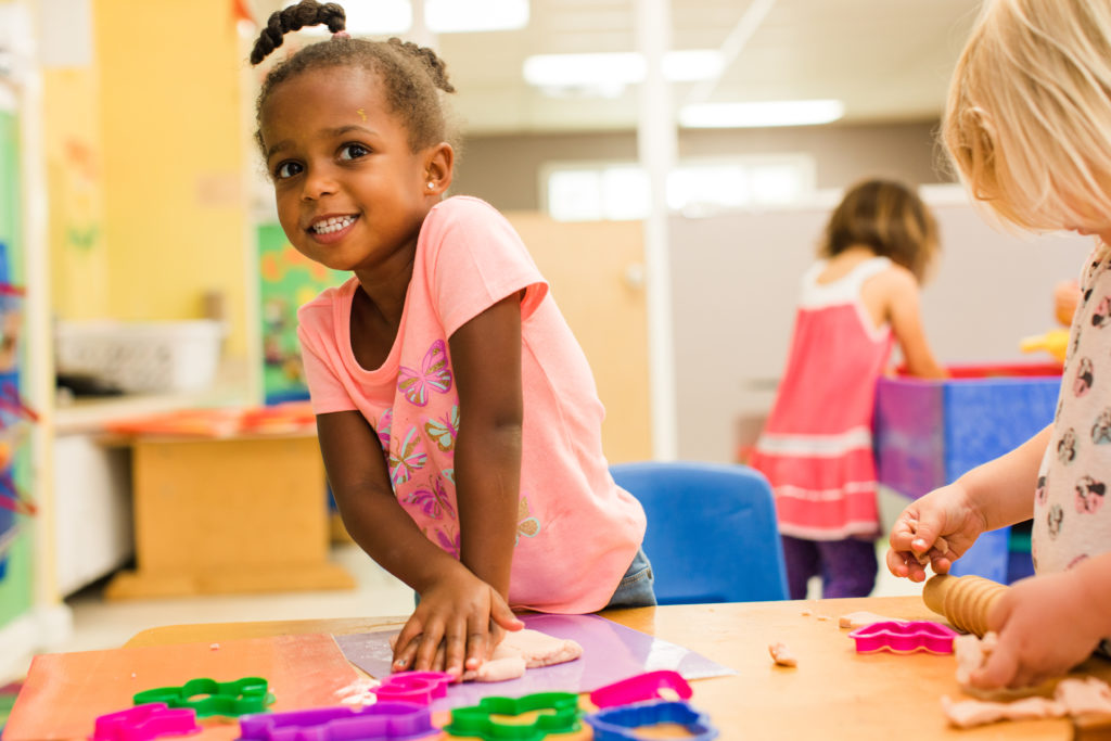 Smiling african american nursery girl pushing a clay on the table while on their clay art activity at a Preschool & Daycare Serving Hampton Roads, VA