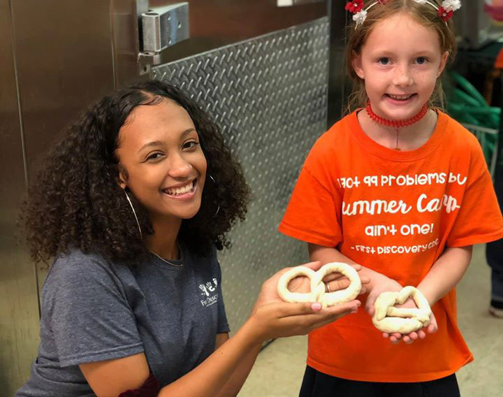 Teacher and a young girl holding a Pretzel for a school project at a Preschool & Daycare Serving Hampton Roads, VA